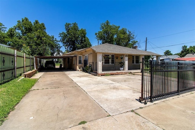 view of front of property with driveway, a fenced front yard, and an attached carport