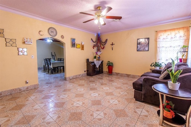 living room with arched walkways, a textured ceiling, light tile patterned flooring, ceiling fan, and ornamental molding