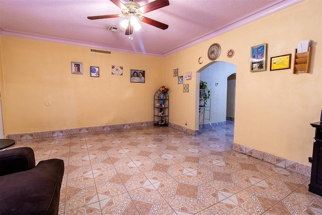 living area featuring arched walkways, a textured ceiling, visible vents, ceiling fan, and crown molding