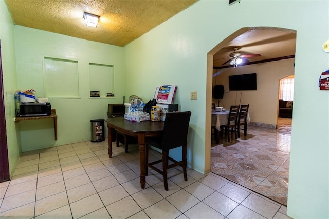 dining room featuring arched walkways, a textured ceiling, a ceiling fan, and light tile patterned flooring