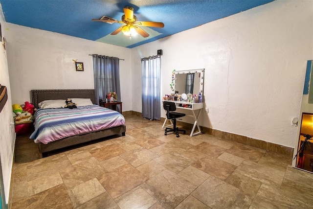 bedroom featuring baseboards, stone finish flooring, and ceiling fan