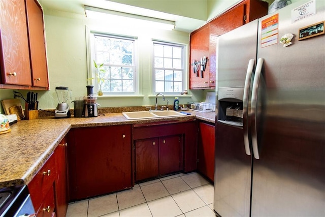 kitchen with appliances with stainless steel finishes, a sink, and light tile patterned flooring