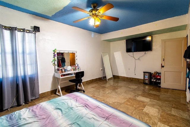 bedroom with baseboards, stone finish floor, and ceiling fan