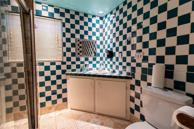 bathroom featuring a stall shower, tile walls, toilet, tile patterned flooring, and vanity