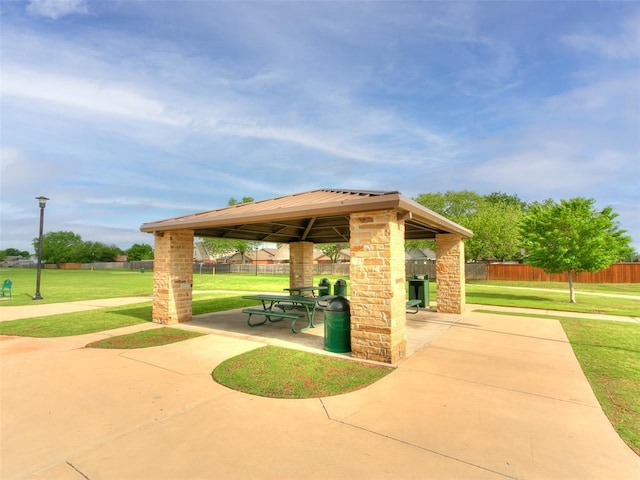 view of property's community featuring fence, a gazebo, a patio area, and a lawn