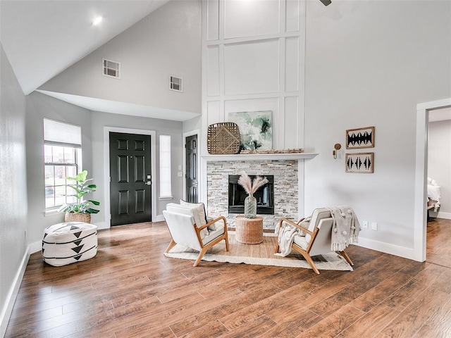 living area with high vaulted ceiling, wood finished floors, and visible vents