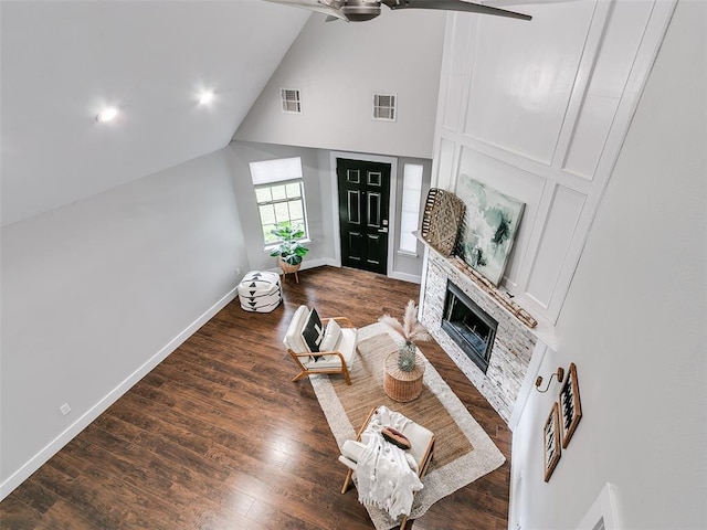 living room with a fireplace, dark wood-type flooring, visible vents, and ceiling fan