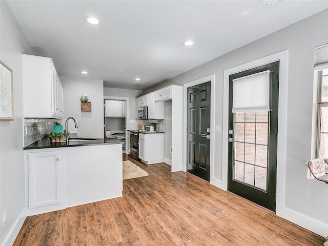 kitchen with stainless steel microwave, electric stove, a sink, a peninsula, and dark countertops