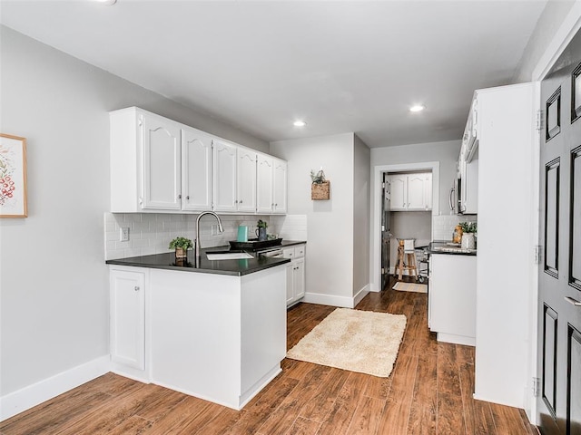 kitchen featuring recessed lighting, a sink, backsplash, white cabinetry, and dark countertops
