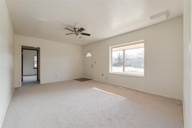 empty room with ceiling fan, light carpet, and baseboards