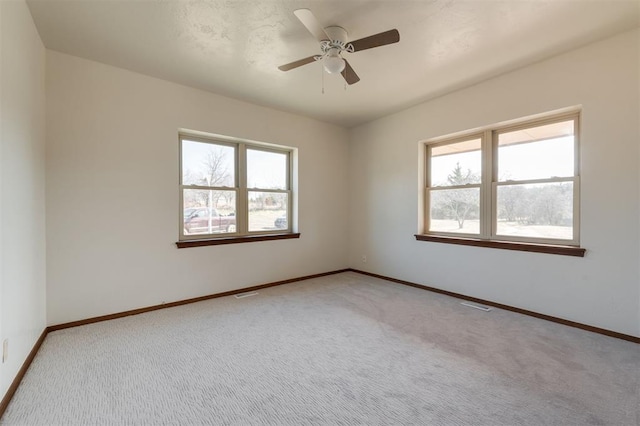 unfurnished room with ceiling fan, baseboards, carpet flooring, and visible vents