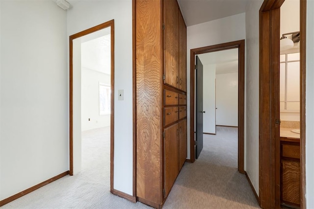 corridor featuring light carpet and baseboards