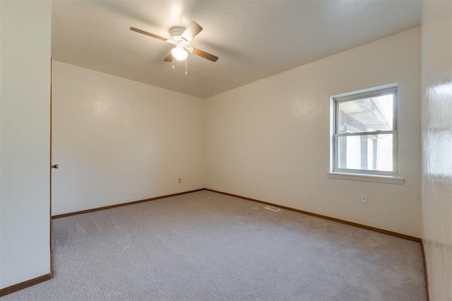 empty room with carpet floors, visible vents, a ceiling fan, and baseboards