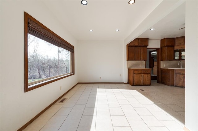unfurnished living room featuring baseboards, a sink, recessed lighting, and light tile patterned floors