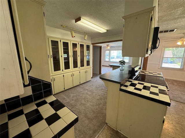 608 Roosevelt St, Seminole, OK 74868 - kitchen featuring tile counters, a textured ceiling, ceiling fan, and a peninsula