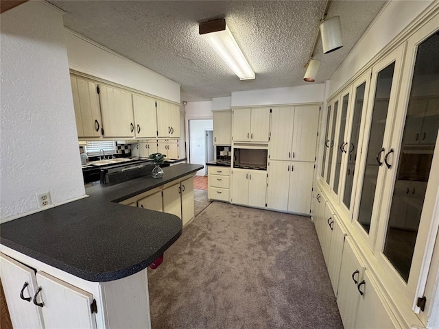 608 Roosevelt St, Seminole, OK 74868 - kitchen featuring dark countertops, a peninsula, a textured ceiling, and cream cabinetry
