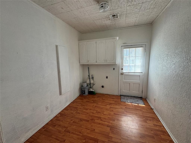 608 Roosevelt St, Seminole, OK 74868 - laundry area with a textured wall, wood finished floors, and visible vents