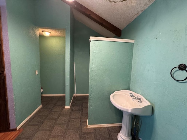 608 Roosevelt St, Seminole, OK 74868 - bathroom featuring vaulted ceiling, a textured ceiling, and baseboards