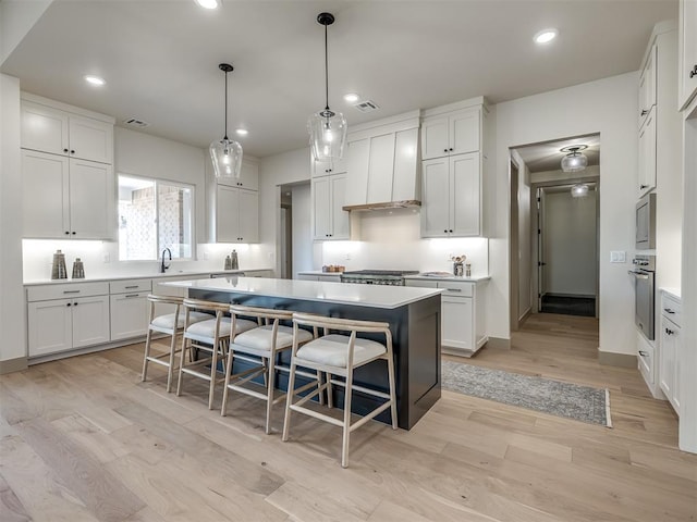 1529 Pedras Pl, Newcastle, OK 73065 - kitchen with a breakfast bar area, a center island, light wood-style floors, white cabinets, and oven