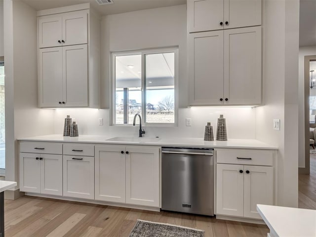 1529 Pedras Pl, Newcastle, OK 73065 - kitchen featuring stainless steel dishwasher, a sink, light wood-style flooring, and white cabinetry