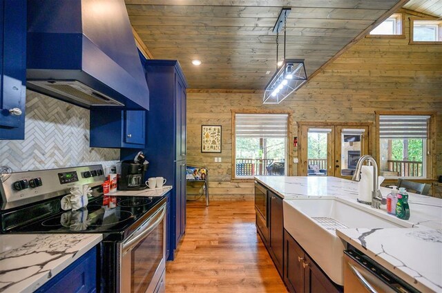 66 Morning Pines Trl, Broken Bow, OK 74728 - kitchen with light wood finished floors, blue cabinetry, premium range hood, stainless steel appliances, and tasteful backsplash