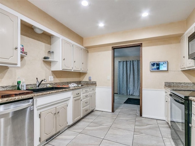 12141 Greenlawn Ave, Oklahoma City, OK 73170 - kitchen with stainless steel dishwasher, a sink, wainscoting, white cabinetry, and black range with electric stovetop