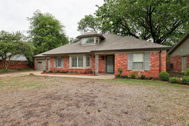 view of front of property featuring driveway, an attached garage, a shingled roof, and brick siding