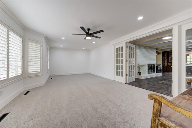 unfurnished room featuring carpet flooring, visible vents, plenty of natural light, ornamental molding, and a ceiling fan