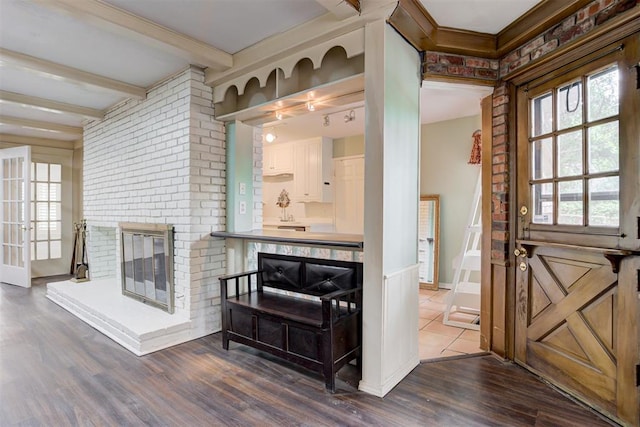 interior space with dark wood finished floors, beamed ceiling, a fireplace, baseboards, and crown molding