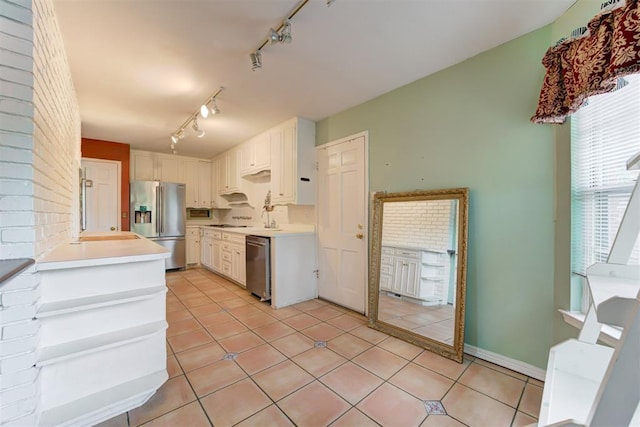 kitchen with appliances with stainless steel finishes, light tile patterned flooring, light countertops, and track lighting