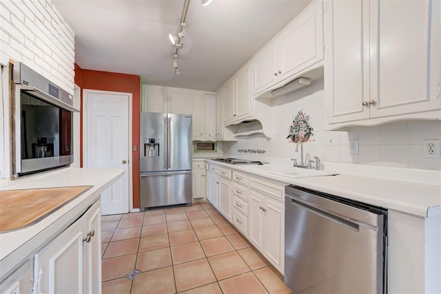 kitchen featuring white cabinetry, stainless steel appliances, decorative backsplash, and a sink