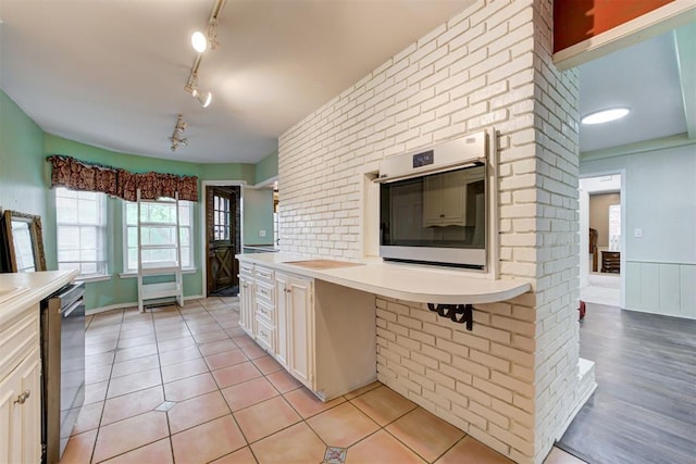kitchen featuring track lighting, stainless steel appliances, light countertops, white cabinets, and light tile patterned flooring