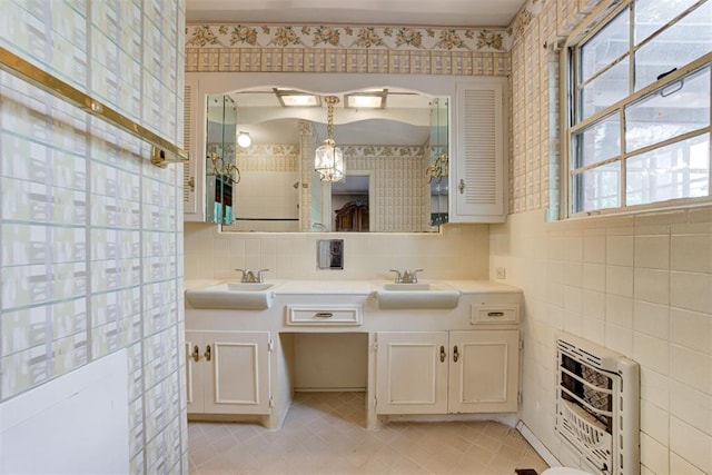 bathroom featuring heating unit, a sink, double vanity, and tile patterned floors