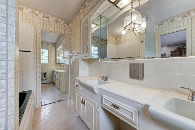 full bathroom featuring a notable chandelier, tile patterned flooring, double vanity, and a sink