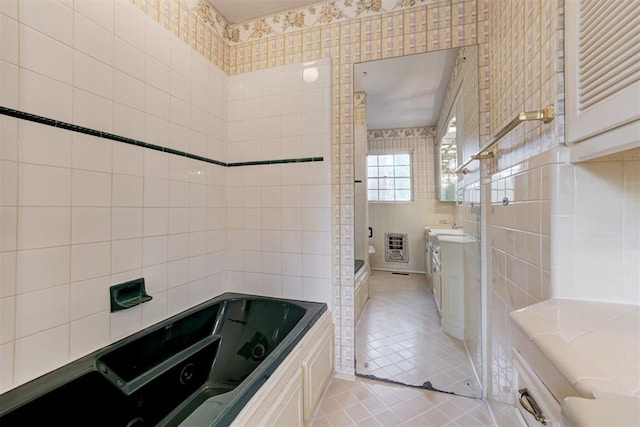 full bathroom featuring tile walls, tile patterned floors, vanity, and a jetted tub