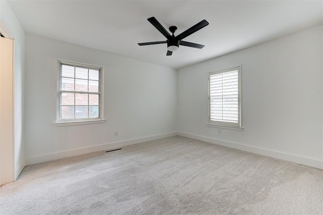 spare room with carpet flooring, a ceiling fan, visible vents, and baseboards