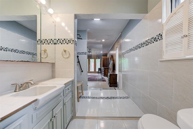 full bathroom featuring tile walls, walk in shower, toilet, and vanity