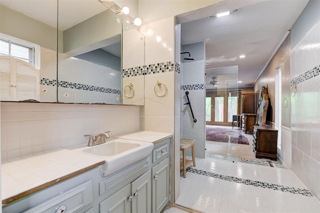 full bathroom featuring tiled shower, ceiling fan, vanity, tile patterned flooring, and backsplash