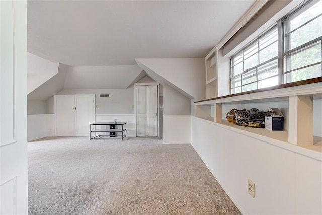 additional living space featuring lofted ceiling, visible vents, and carpet floors