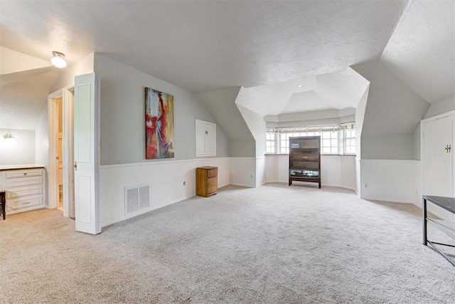 bonus room featuring lofted ceiling, carpet, visible vents, and baseboards