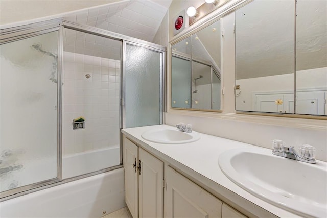 bathroom featuring bath / shower combo with glass door, double vanity, vaulted ceiling, and a sink
