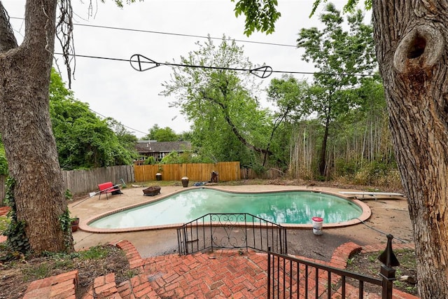 view of swimming pool featuring a diving board, a patio, a fenced in pool, and fence