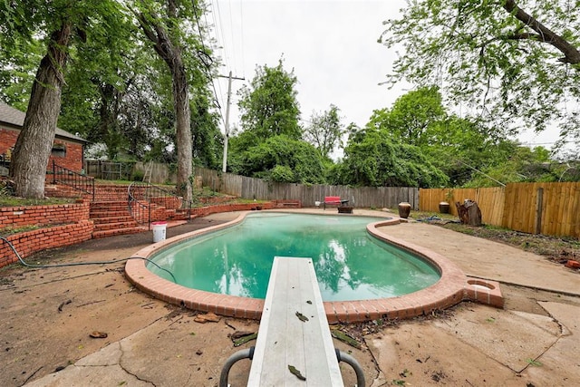 view of pool with a patio, a fenced in pool, a fenced backyard, and a diving board