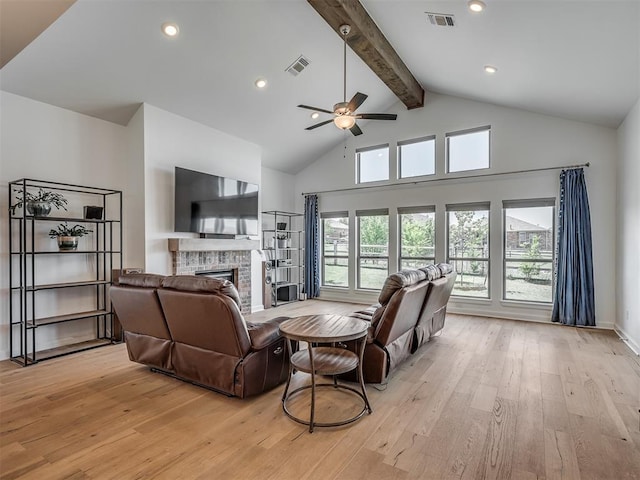 living room featuring a ceiling fan, light wood-style flooring, visible vents, and a fireplace