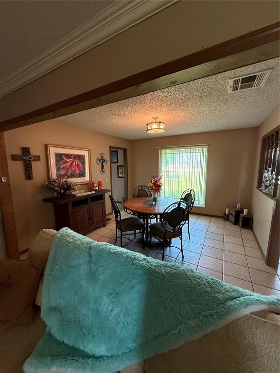 4108 N Broadway Ave, Hinton, OK 73047 - dining space featuring light tile patterned floors, a textured ceiling, visible vents, and ornamental molding