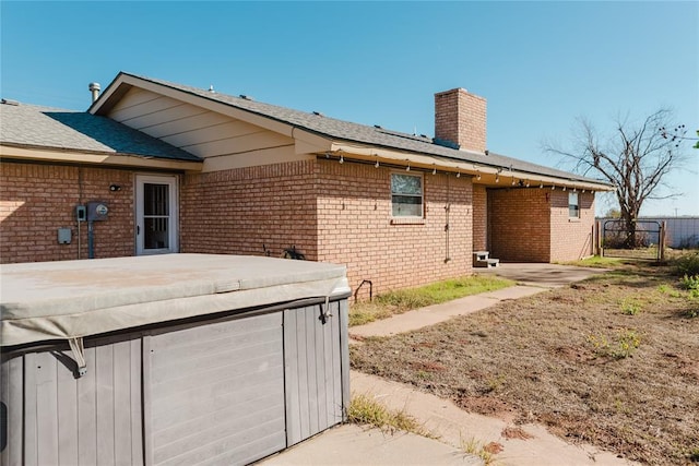4108 N Broadway Ave, Hinton, OK 73047 - back of house with a chimney, brick siding, fence, a hot tub, and roof with shingles