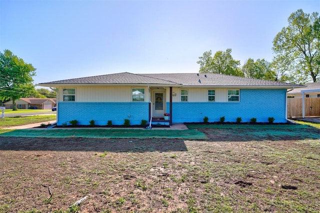 ranch-style house featuring brick siding, a front lawn, and fence