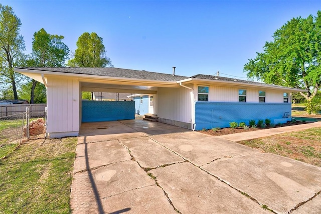 ranch-style house featuring a carport, concrete driveway, and fence