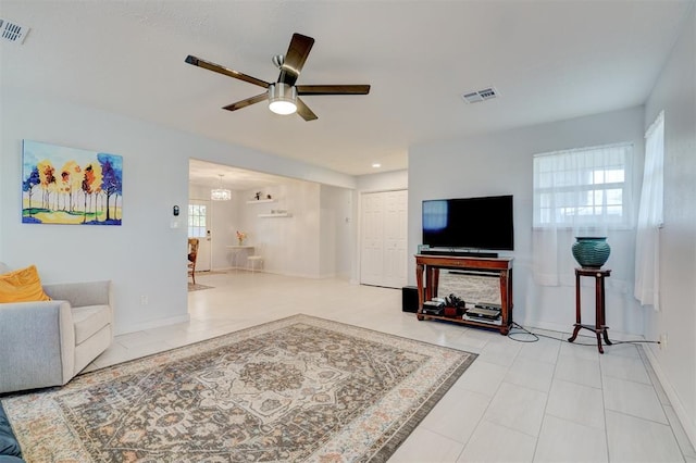 tiled living area with baseboards, a ceiling fan, and visible vents