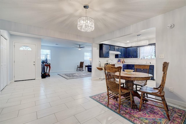 dining area with baseboards and ceiling fan with notable chandelier